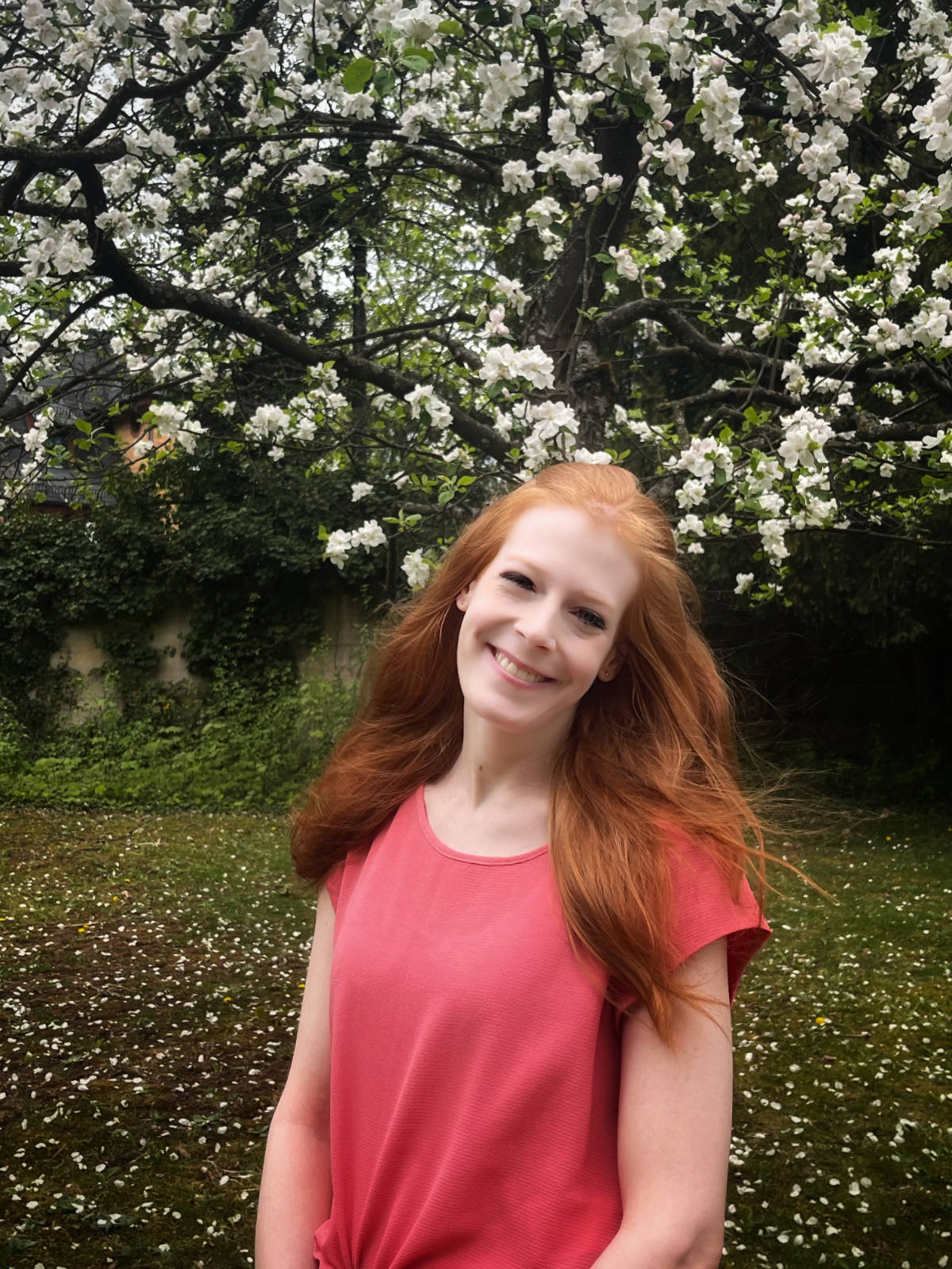 Miri steht vor einen blühenden Apfelbaum.